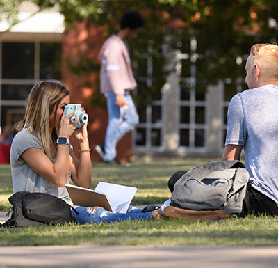 Campus Life Events Student taking a picture of friends on campus lawn