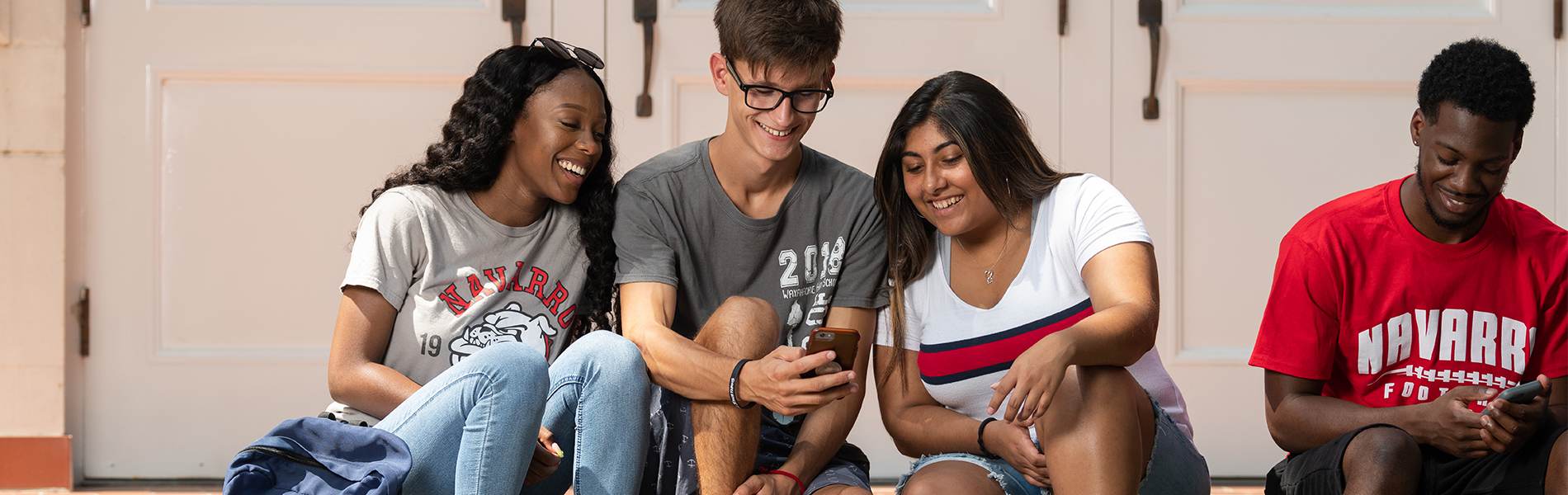 皇冠博彩基金会 Group of 皇冠博彩 students sitting on front steps of the building, laughing and interacting with each other.
