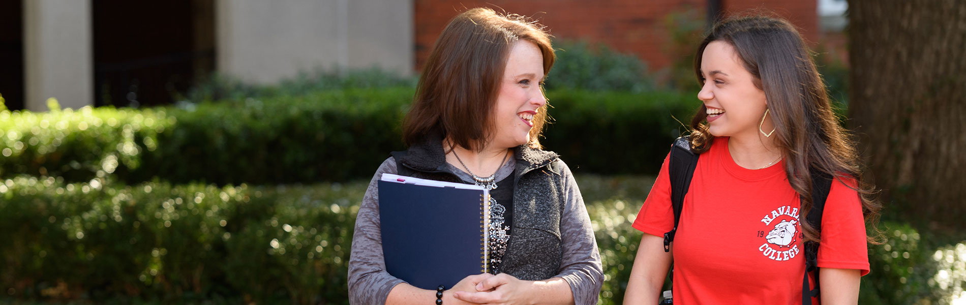 被录取的学生 Students laughing and talking as the are walking through the courtyard.
