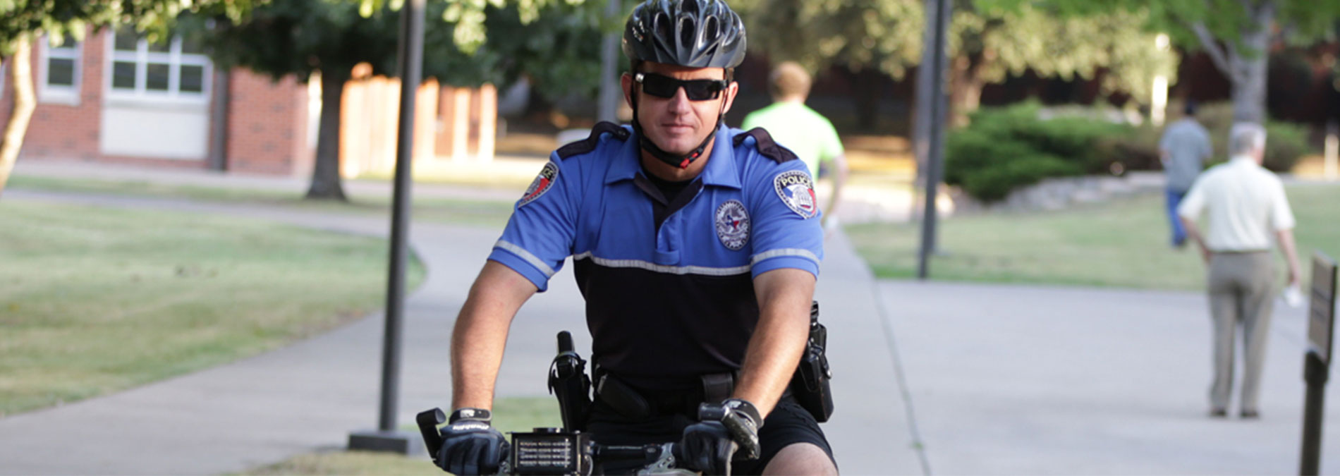 皇冠博彩 Police Officer patrolling campus sidewalk on a bicycle.