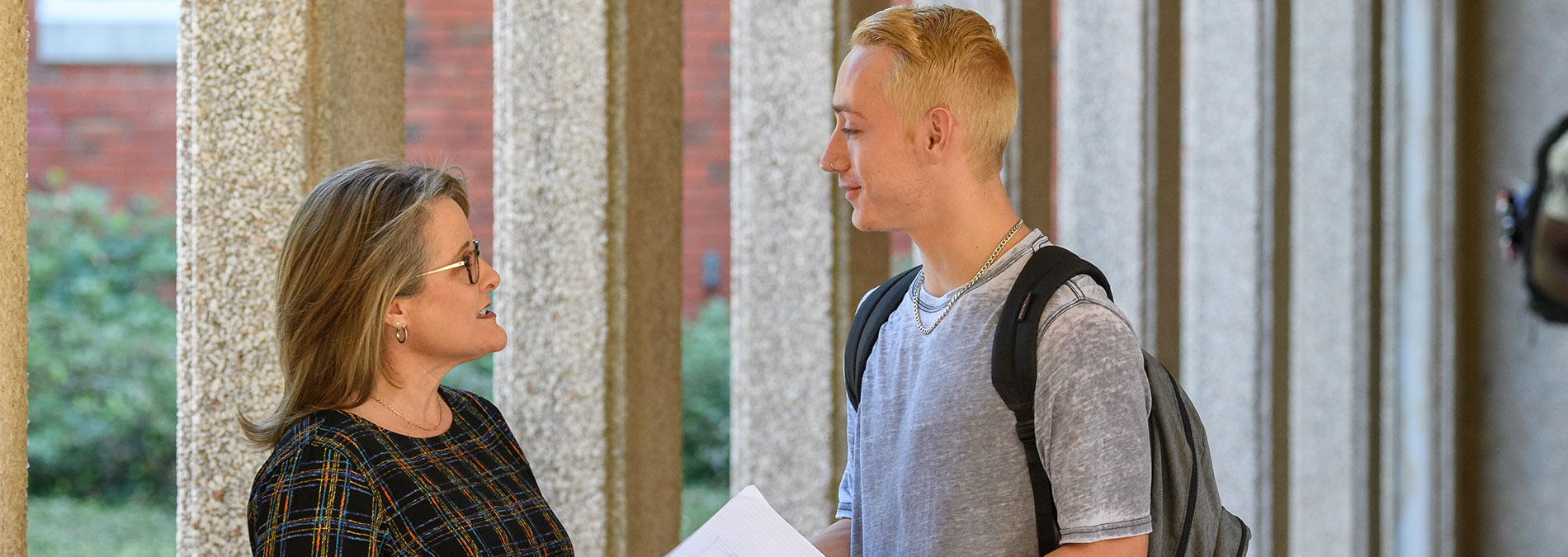 健康与咨询 An employee talking to a student outside the building