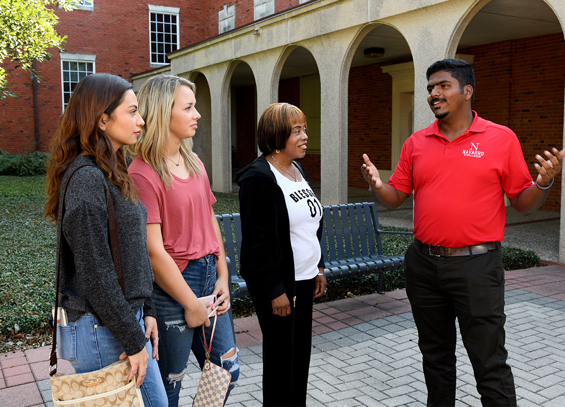 Walking Tour Recruiter talking to two prospective students and a chaperone.