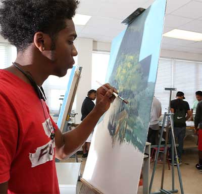 皇冠博彩 Visual Arts Student painting on a canvas