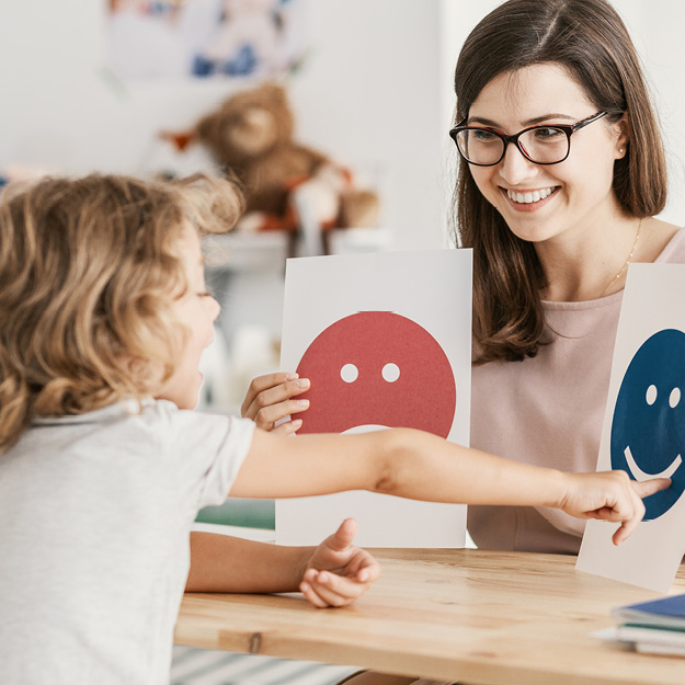 Psychology Psychologist showing a child two emotional pictures