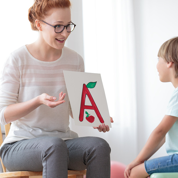 Speech Teacher holding a sign with letter A to a child